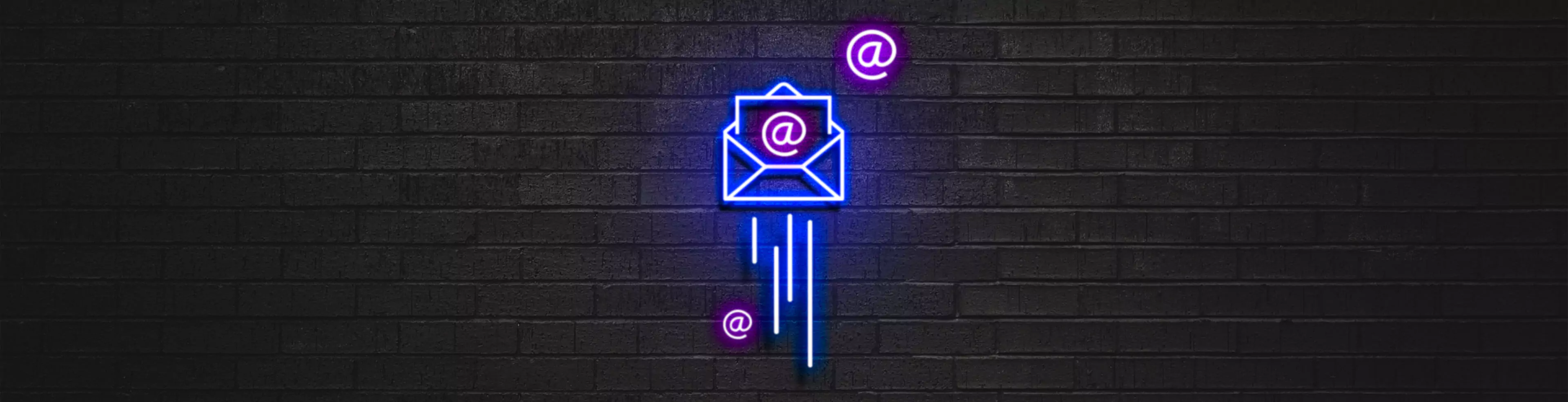 Neon de envelope iluminando uma parede de tijolos escura